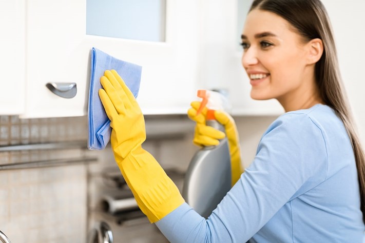 Woman cleaning and sanitising kitchen cabinets