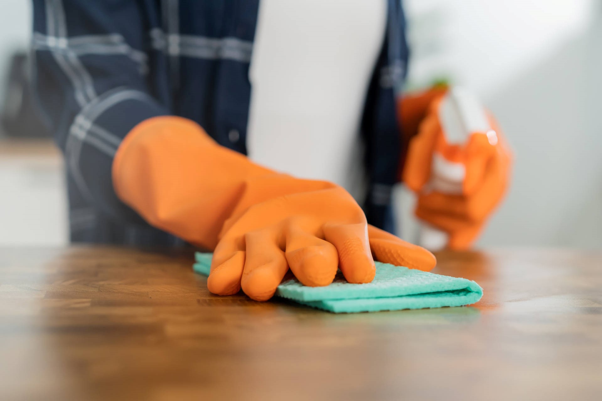 Person in orange gloves cleaning a surface